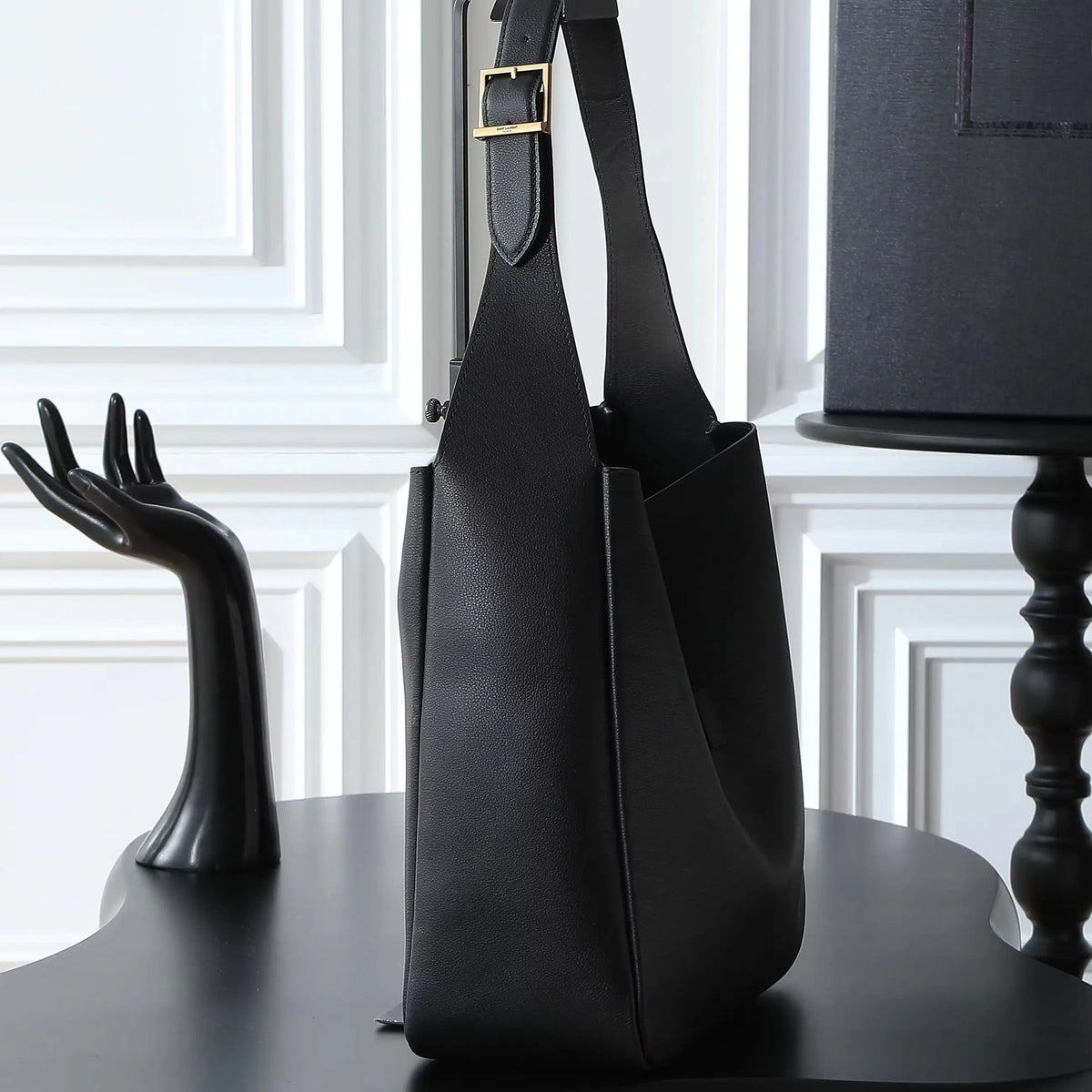 Bolsa de ombro grande em couro preto de grão macio, com alça larga ajustável e design aberto.