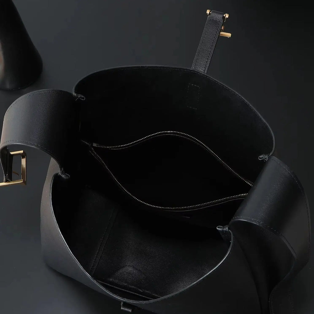 Bolsa de ombro grande em couro preto de grão macio, com alça larga ajustável e design aberto.